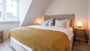 Une chambre à coucher avec un lit, deux lampes de chevet, une fenêtre et une vue sur l’extérieur.