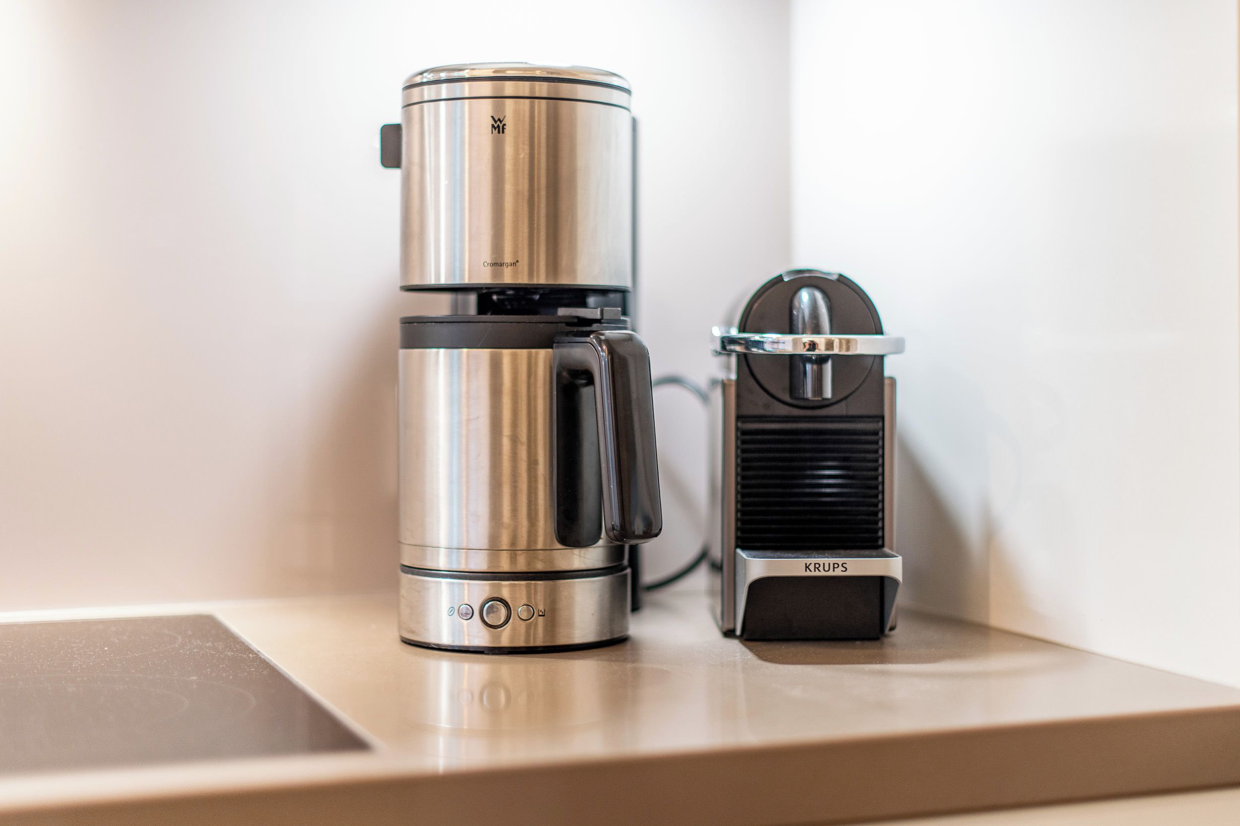 A stainless steel coffee maker and a KRUPS coffee grinder on a countertop.