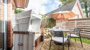 Une terrasse avec une table et des chaises, un panier en osier et un mur en pierre.