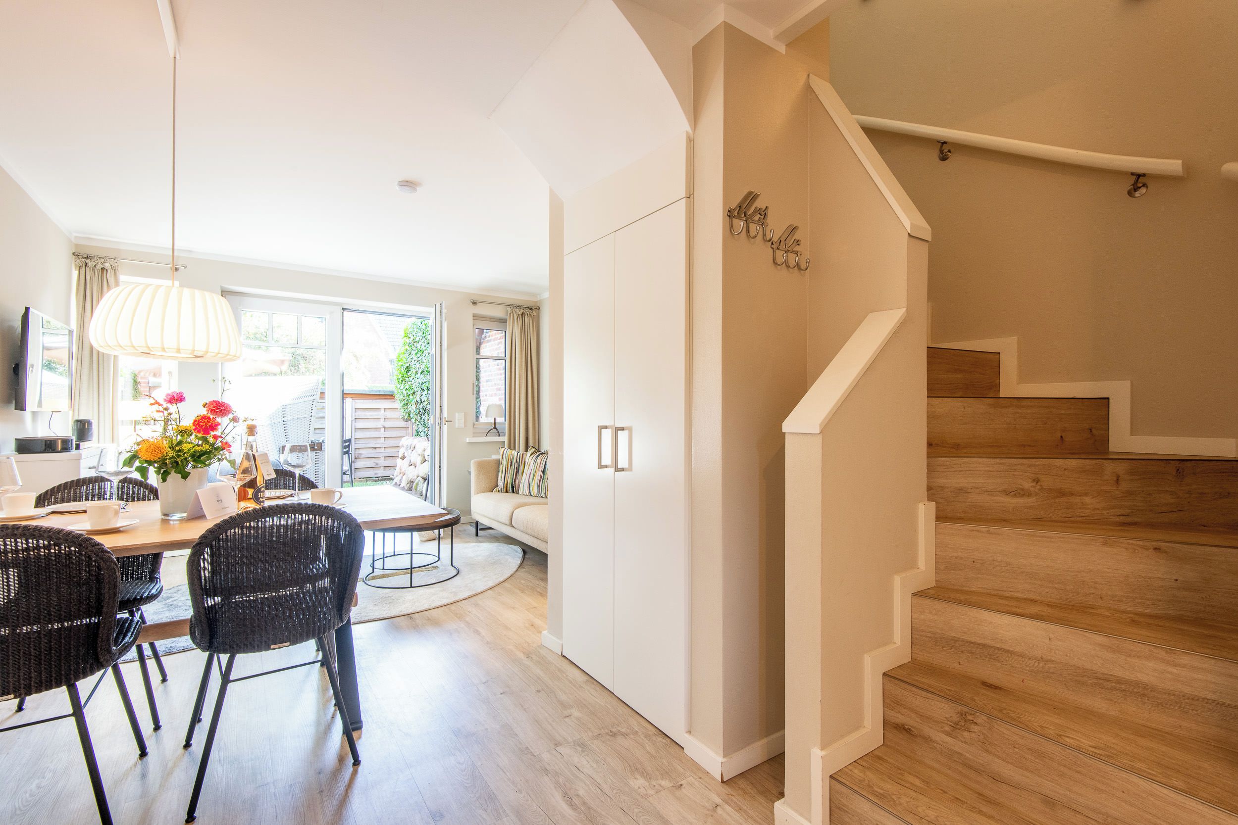 A modern interior with a dining area, a staircase, and a view of the outdoors.