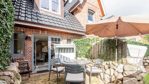 Une terrasse avec une table et des chaises, un mur en pierre et une clôture en bois.