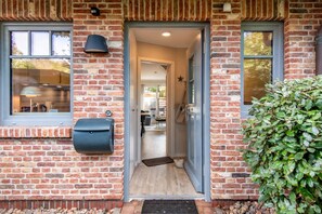 A brick building entrance with a mailbox, a door, and a small garden.