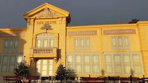 Un edificio amarillo con el letrero 'Eden Theatre' en la fachada, que cuenta con grandes ventanales y un balcón.