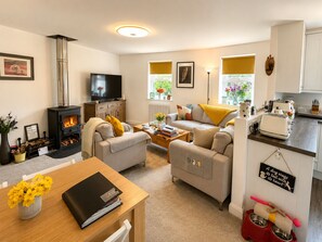 A cozy living room with a fireplace, a television, and a sofa. - Muddy Boots – Scarpa. (Kirkby Stephen)
