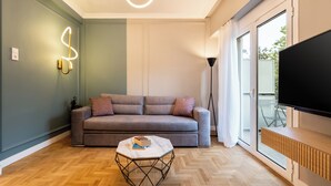 Een moderne woonkamer met een grijze bank, een marmeren salontafel en een flatscreen televisie.