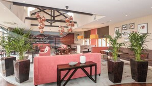 Een moderne hotel lobby met een centraal zitgedeelte, grote ramen en decoratieve planten.