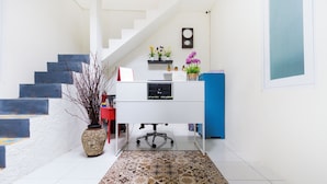 A modern office space with a white desk, a chair, a vase with branches, and a patterned rug. - OYO 2975 House Of Mahira Syariah (Baregbeg)