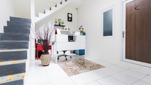 A modern interior with a staircase, a desk with a computer, a potted plant, and a door labeled 'C'. - OYO 2975 House Of Mahira Syariah (Baregbeg)