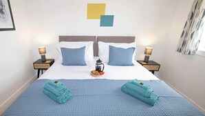 A hotel room with a bed, two nightstands, a coffee pot, and towels. - Cozy Dundee Apartment With a View (Dundee)