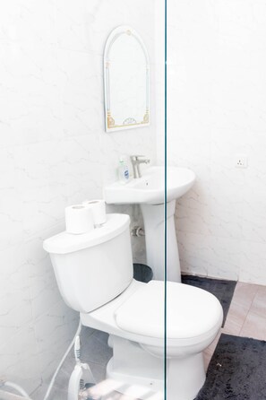 A bathroom with a toilet, sink, and a mirror. - Legit Luxury Apartments in Accra, Dome Pillar2 (Accra)