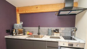 A modern kitchen with a built-in oven, a coffee maker, and a sink. - Daffodil (Welshpool)