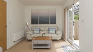 Ein Wohnzimmer mit einem beigen Sofa, einem Holztisch und einem großen Fenster.