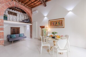 A dining area with a table set for four, a sofa, and a painting on the wall.