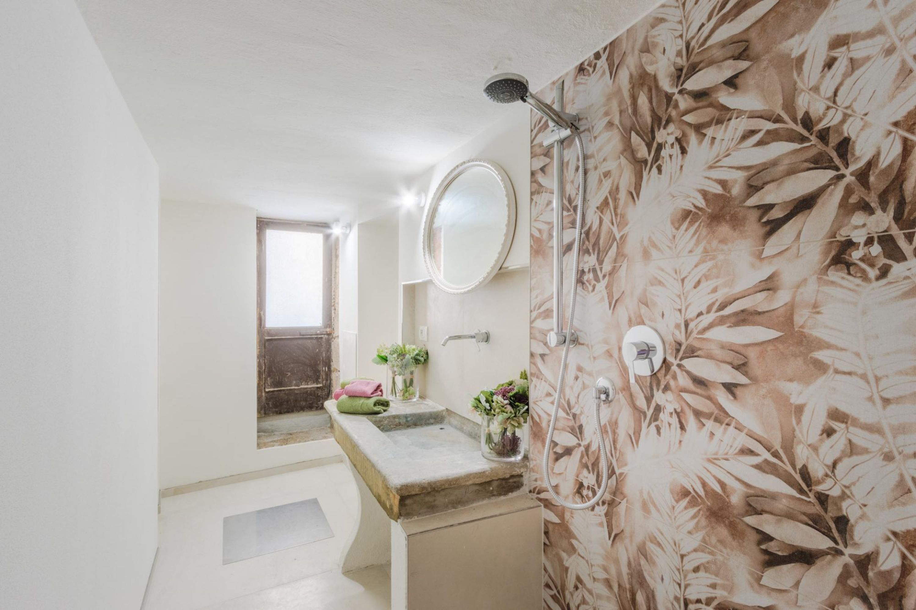 A bathroom with a shower, a sink with a mirror, and a window.