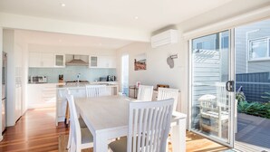 A modern kitchen with white cabinetry, a central island, and a dining area with white chairs.