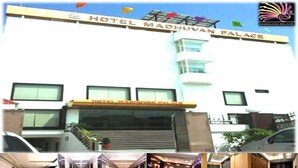 Hotel Madhuvan Palace with a modern facade, a central staircase, and a view of the interior including a lobby and a bedroom. - Hotel Madhuvan Palace (Varanasi)
