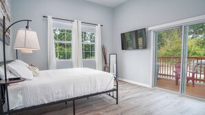 A bedroom with a bed, a nightstand, a lamp, a window, and a sliding glass door leading to an outdoor deck. - Charming 3br/2ba Gem Close to Downtown/ Riverwalk (San Antonio)