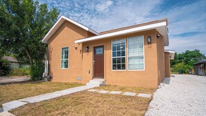 A single-story house with a brown exterior, a front door, and a small front yard with a gravel path leading to the door. - Charming 3br/2ba Gem Close to Downtown/ Riverwalk (San Antonio)
