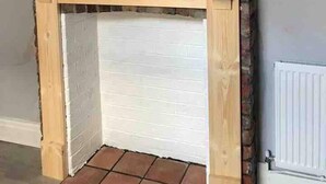 A corner room with a brick wall, a wooden mantel, and a white door. - Sleeps 14 Cardiff City Centre (Cardiff)