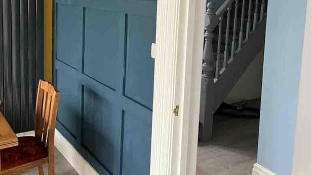 A room with a blue paneled wall, a wooden dining table with chairs, and a staircase leading to an upper level. - Sleeps 14 Cardiff City Centre (Cardiff)