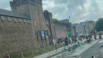 A historic stone wall with a tower, a paved walkway, and a bike lane.