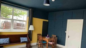 A room with a dining table, chairs, a bench with cushions, a lamp, and a window with curtains. - Sleeps 14 Cardiff City Centre (Cardiff)
