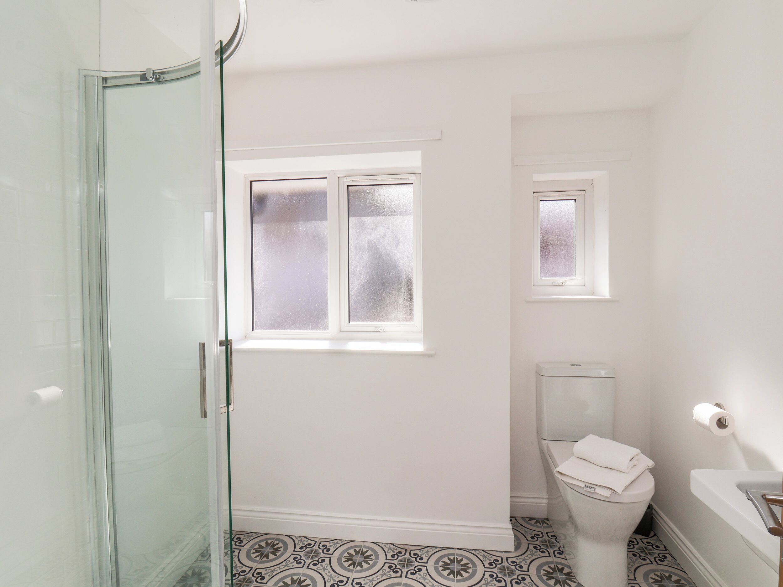 A bathroom with a toilet, a small window, and a shower area.