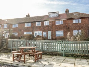 A two-story brick house with a front garden, a wooden fence, and a picnic table. - Whitby View (Whitby)