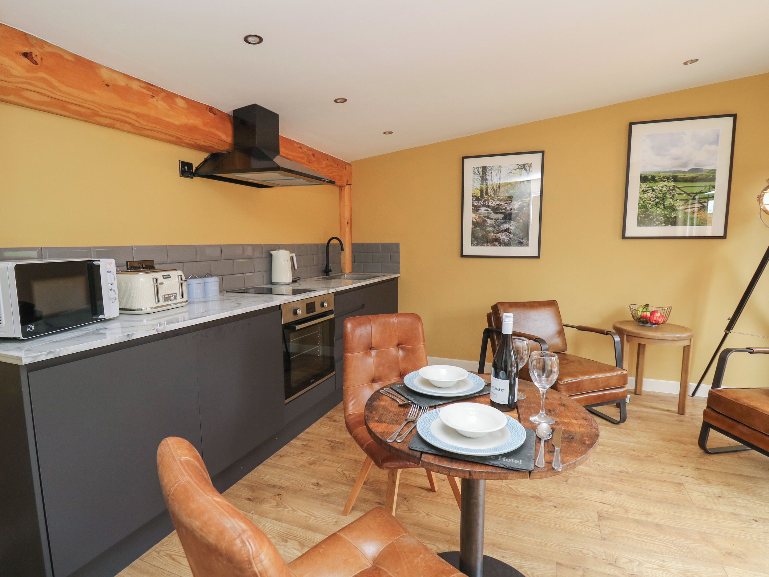 A compact kitchen with modern appliances, a dining area with leather chairs, and a small table set for two.