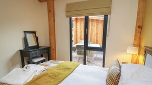Een slaapkamer met een bed, een nachtkastje met spiegel, een raam met uitzicht en een lamp op de nachtkast.