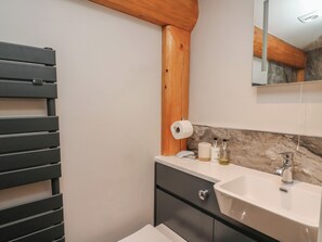 A bathroom with a black towel rack, a white sink, and a mirror above it.