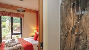 A bedroom with a bed, a window, a nightstand, and a red throw blanket. - Fioled (Welshpool)