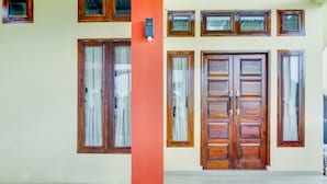 A building facade with multiple windows and doors, a red pillar, and a light fixture. - OYO 3015 Galliano Homestay Syariah (Bukittinggi)