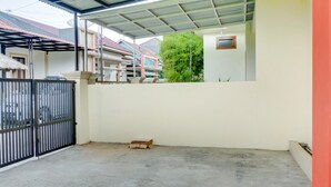 A covered outdoor area with a concrete floor, metal gate, and a small wooden structure. - OYO 3015 Galliano Homestay Syariah (Bukittinggi)