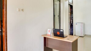 A hotel room with a wooden desk, a laptop, a refrigerator, and a mirror. - OYO 3015 Galliano Homestay Syariah (Bukittinggi)