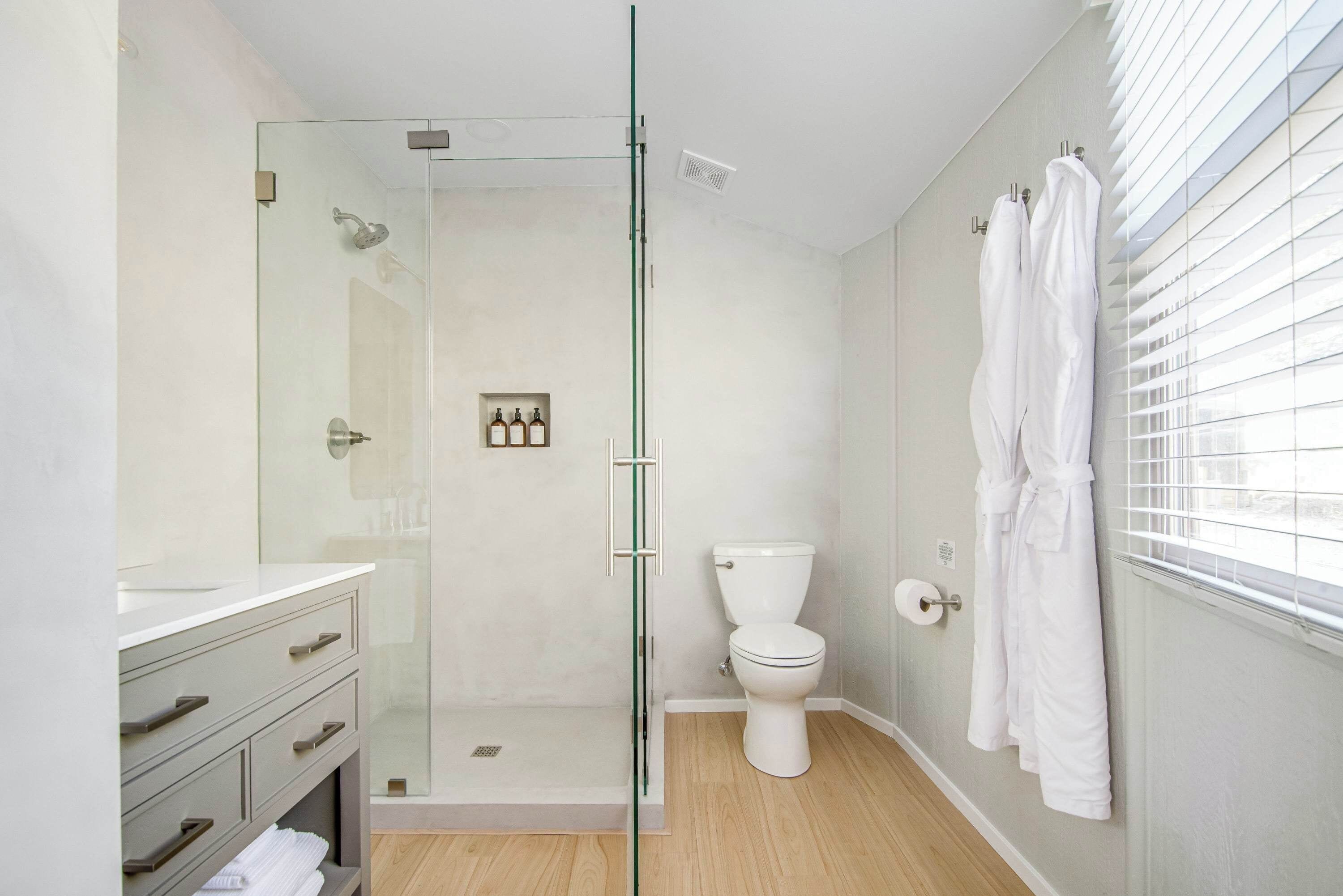 Een moderne badkamer met een douchecabine van glas, een toilet en een wastafel met lades.