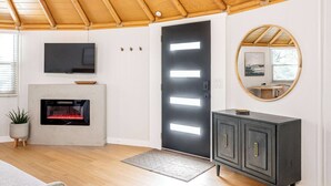Ein modernes Wohnzimmer mit Kamin, Fernseher, einem dunklen Schrank und einem runden Spiegel an der Wand.