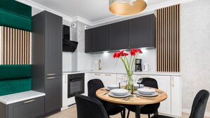 A modern kitchen with dark cabinets, a wooden dining table, and black chairs.