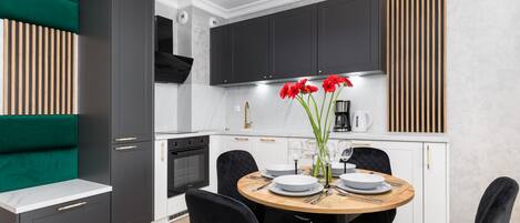A modern kitchen with dark cabinets, a wooden dining table, and black chairs.