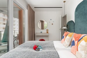Vibrant bedroom with a teal accent wall, colorful pillows, and elegant bedside lamps.
