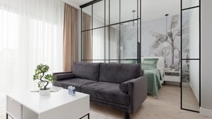 Un salon moderne avec un canapé gris, une table basse blanche et une plante en pot.