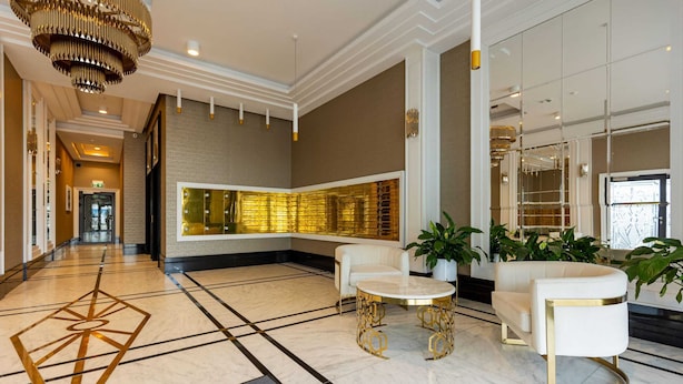 Un hall d’entrée spacieux avec un sol en marbre, un canapé blanc, une table ronde et un grand miroir.
