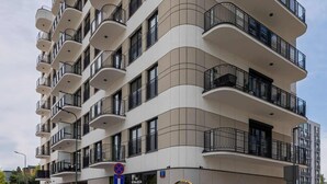 Un hôtel à plusieurs étages, doté de balcons, d’un logo sur la façade et d’un panneau de signalisation bleu indiquant l’emplacement du parking.