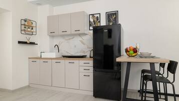 A modern kitchen with a black refrigerator, light-colored cabinets, and a dining area with a table and chairs.