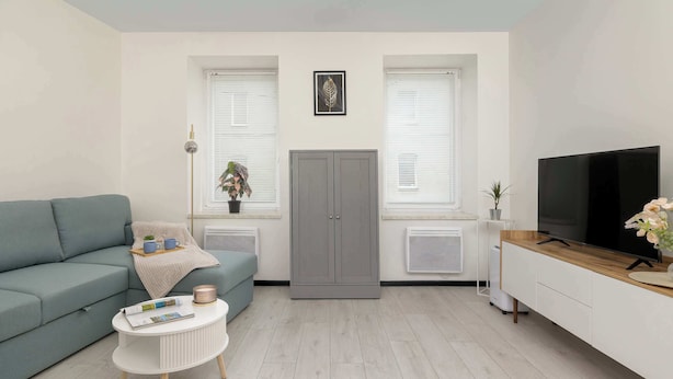 Un salon comprenant un canapé, une table basse, un téléviseur et un meuble.