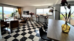 Un soggiorno moderno con pavimento a scacchi, una zona pranzo e un'ampia finestra con vista.