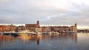 Un porto turistico con imbarcazioni ormeggiate, edifici sullo sfondo e un cielo nuvoloso.