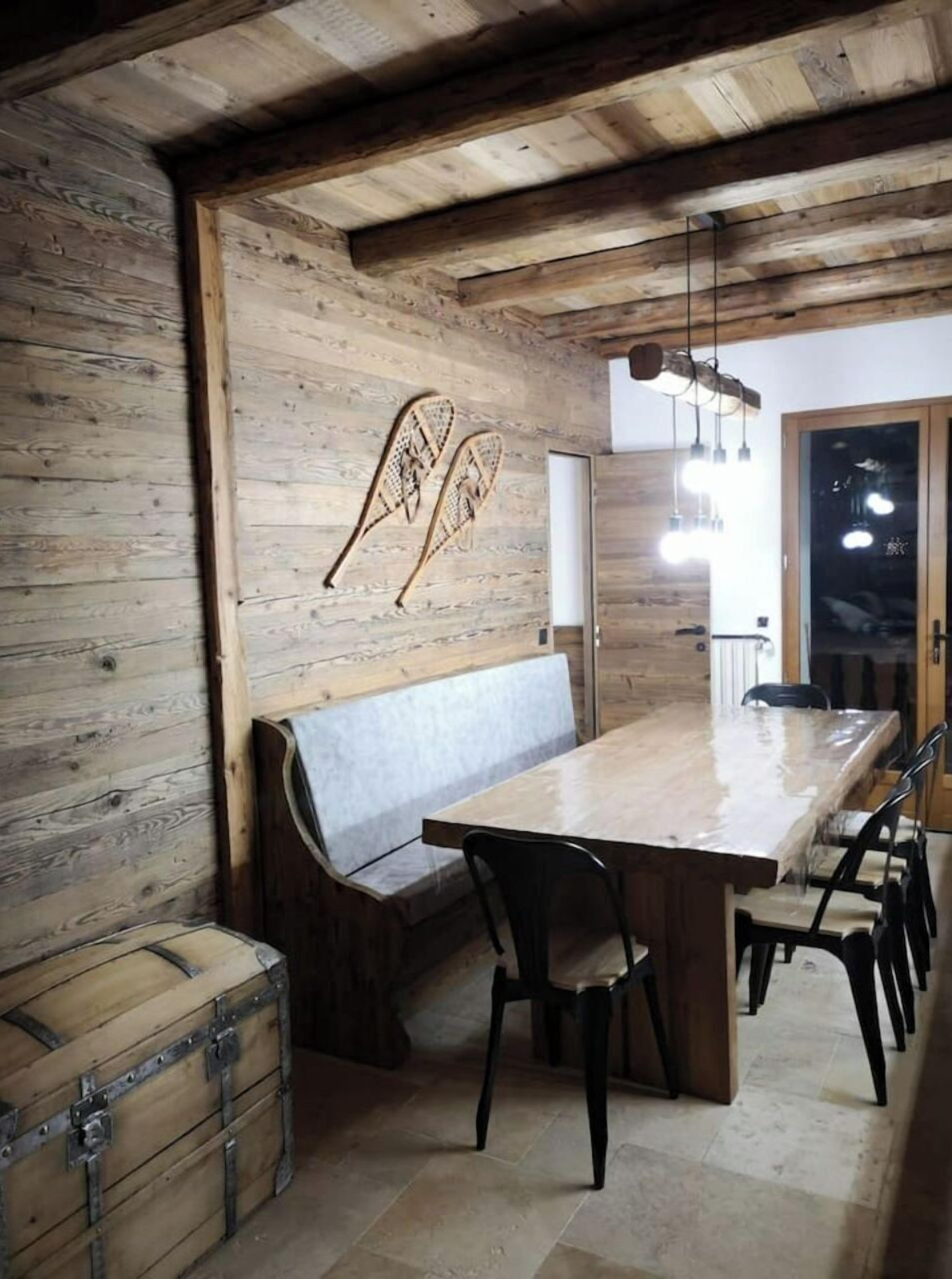 A rustic dining area with a wooden bench, a long table, and chairs.