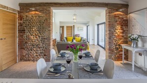 Un comedor con pared de piedra, puerta de madera y una mesa para cuatro, decorada con un florero.