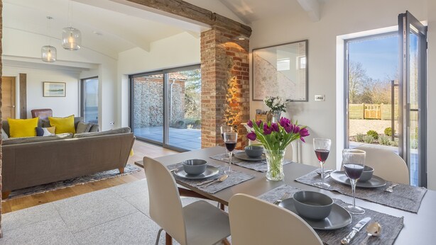 Comedor con un pilar de ladrillo, una mesa dispuesta para cuatro comensales y vistas al exterior.